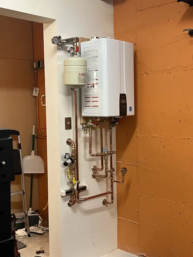 Plumbing technician inspecting water heater connections in White Pigeon